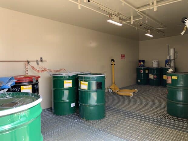 Interior photo of US Chemical Storage building for American Emergency Vehicles. Interior lighting illuminates 55 gallon drums with grounding buss bars as well as other equipment safe within
